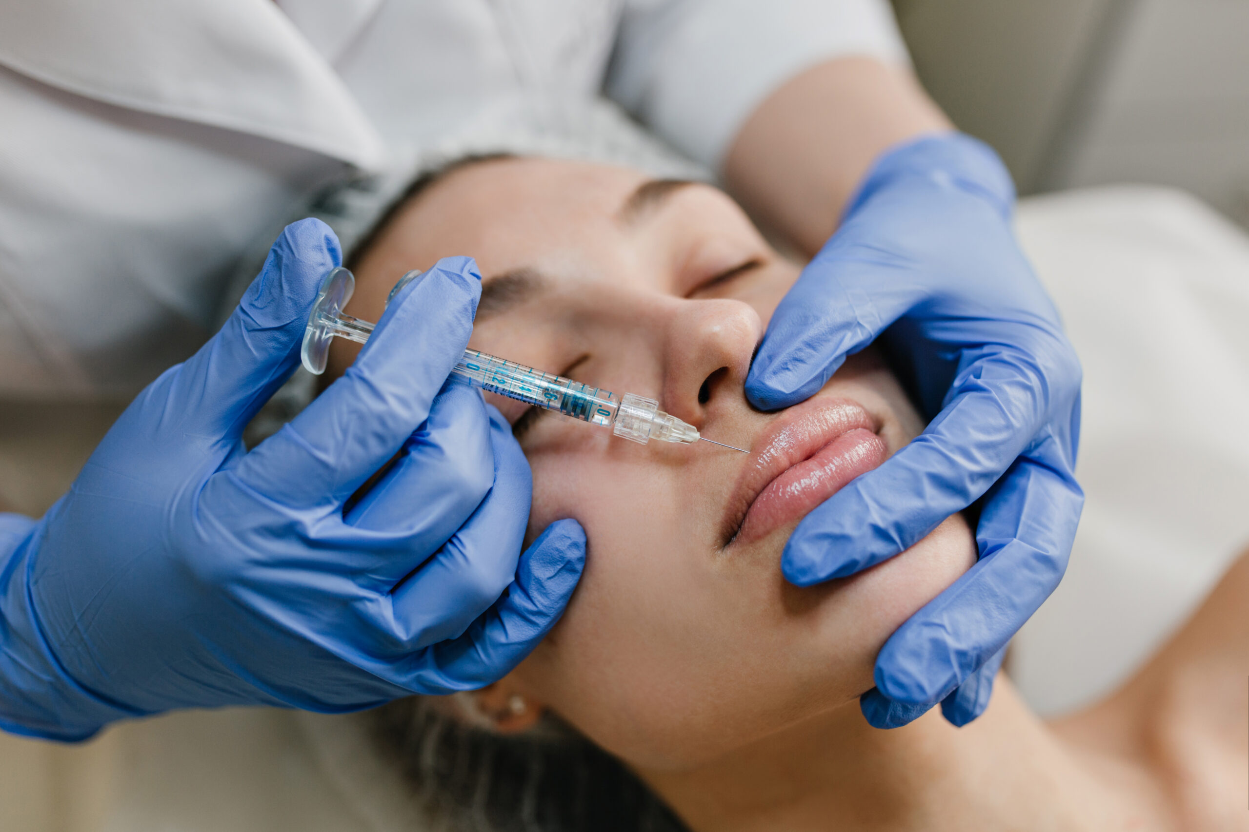 Closeup portrait young woman doing botox procedures by professional. Injection, making lips, modern devices, technology, medicine, cosmetology therapy