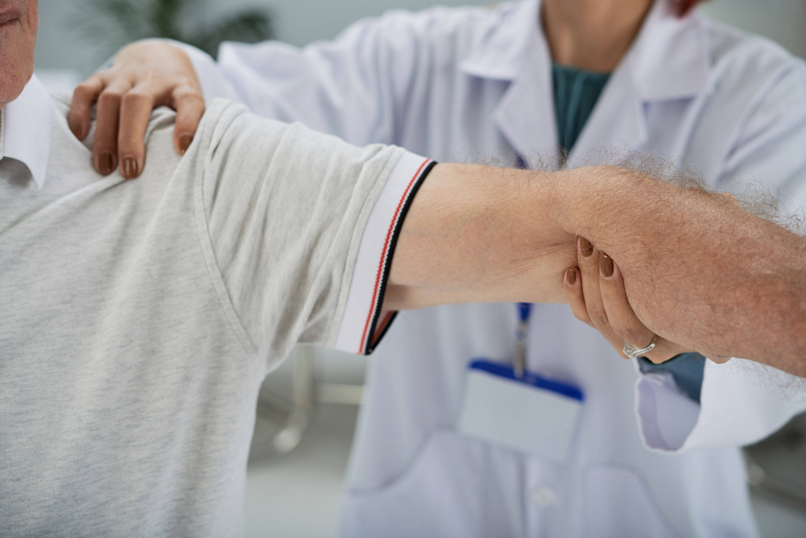 Senior man having shoulder and arm treatment in medical office